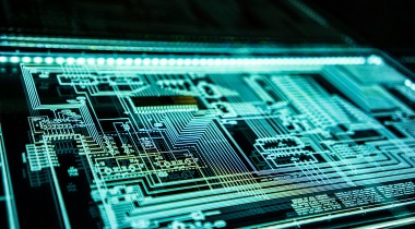 Circuito electrónico digital iluminado en tonos verdes y azules que representa arquitectura tecnológica y sistemas computacionales.