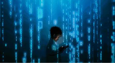 Persona revisando su celular frente a una pantalla digital